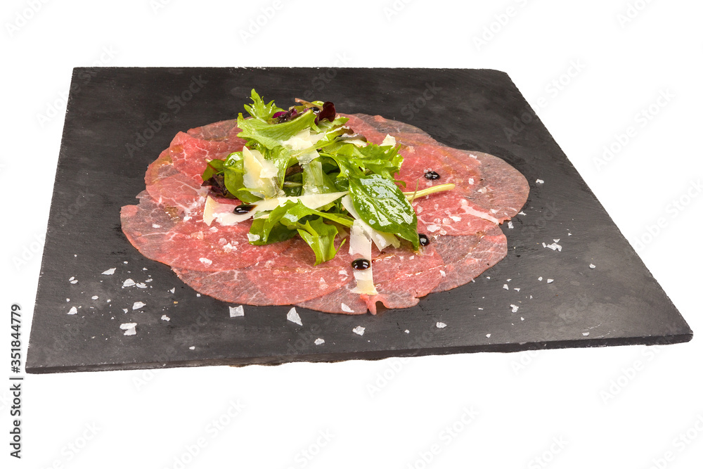 Gourmet Carpaccio with arugula, on a black stone plate, isolated on white background Gourmet Carpaccio with arugula, on a black stone plate, isolated on white background