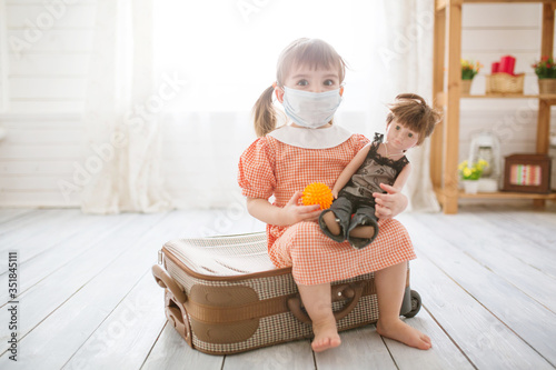 Little cute kid girl in quarantine at home dreams of traveling. photo