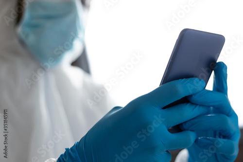 doctor with protective clothing for covid-19 watching the mobile phone in the operating room