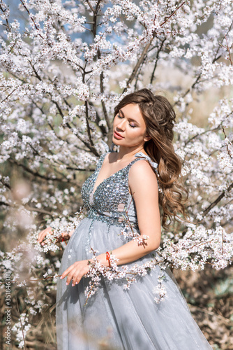 Portrait of a pregnant woman in a blooming spring garden
