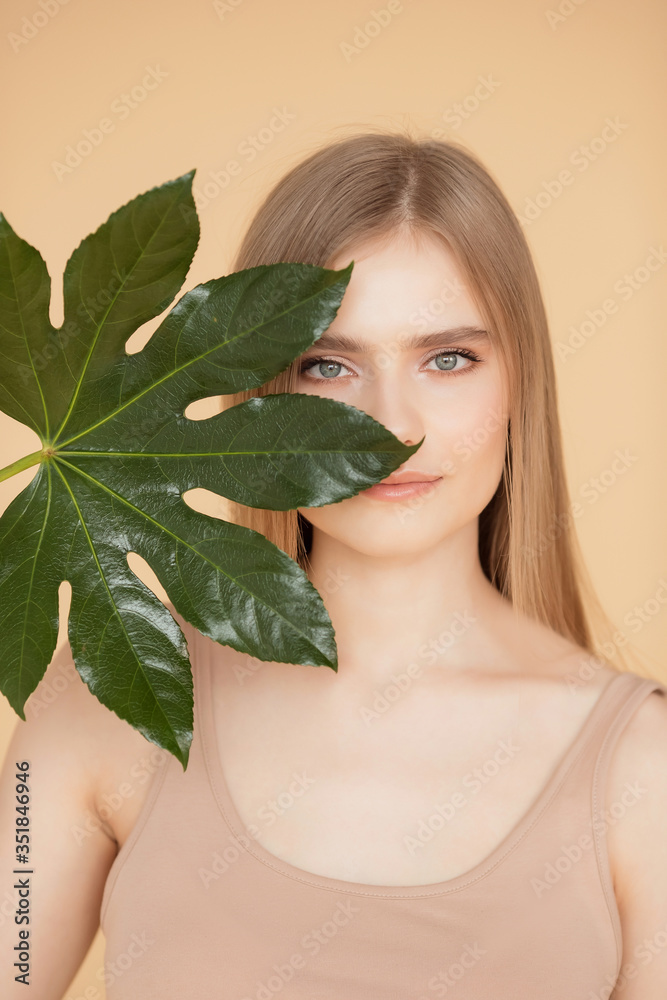 Portrait woman with natural green leaf, blond model girl with clear skin face. Concept Fashion flora beauty Portrait woman with natural green leaf, blond model girl with clear skin face. Concept Fashion flora beauty