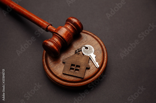 Judge gavel and key chain in shape of two splitted part of house on wooden background. Concept of real estate auction or dividing house when divorce, division of property, real estate, law system. photo