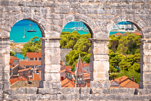 Trogir old city rooftops and turquoise archipelago view through stone windows photo