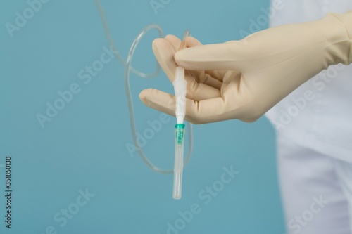 dropper catheter in the hands of a doctor on a blue background