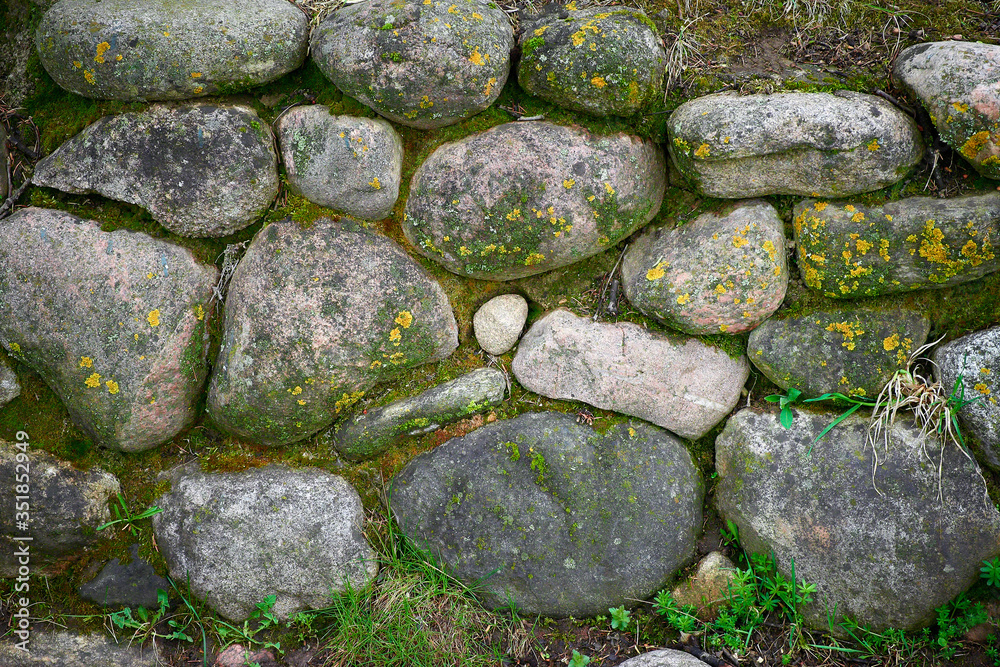 Old stone wall of stones with moss and grass