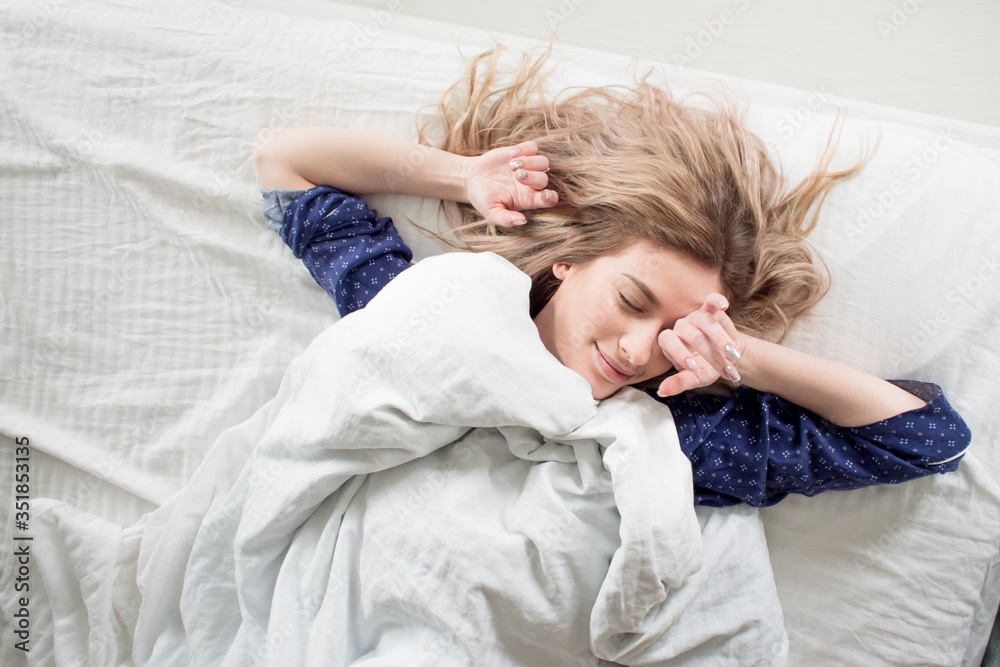 Cute blonde in her bed in blue pajamas, under a blanket Cute blonde in her bed in blue pajamas, under a blanket