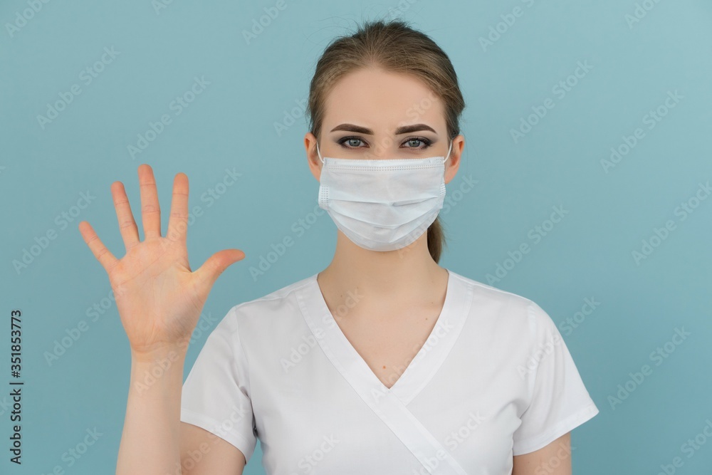 woman doctor in mask shows points from 1 to 5 with a hand on a blue background woman doctor in mask shows points from 1 to 5 with a hand on a blue background