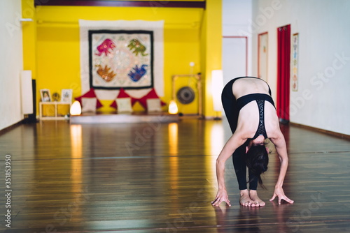 Woman doing yoga in a yoga school with her hands resting on the floor.