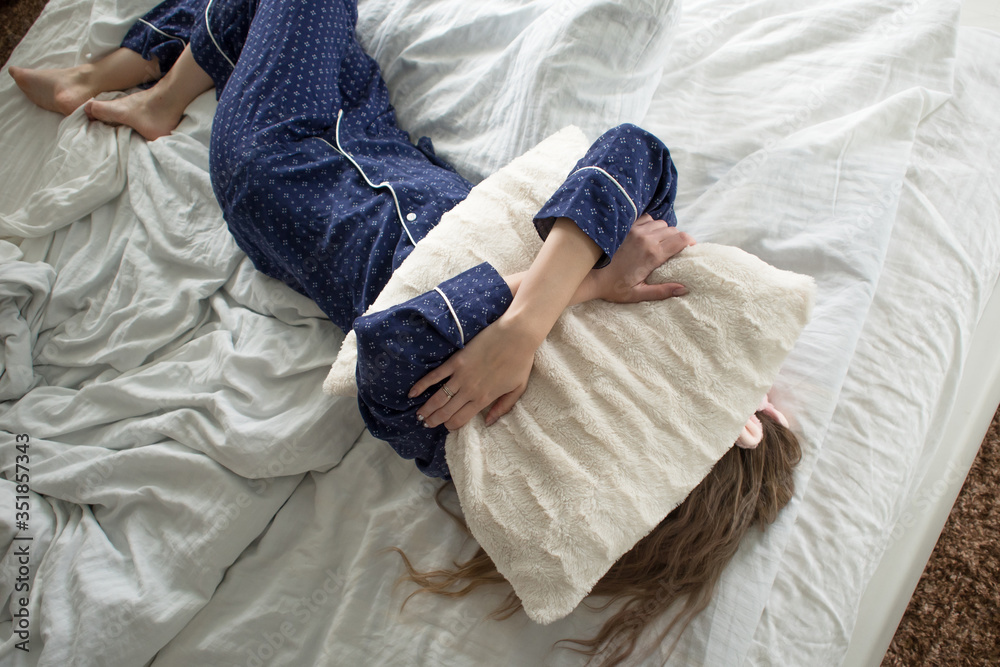 Too lazy to get out of bed, a woman covers her face with a pillow