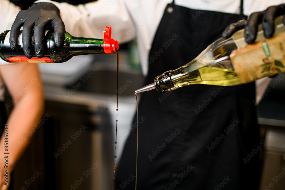 Fototapeta premium chef pours oil from bottle for barbecue
