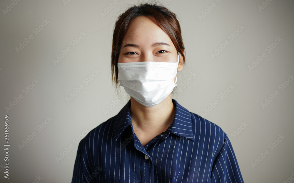 Asian, Thai woman wearing a medical face mask protection in prevention for coronavirus or COVID-19 on a white wall background in studio portrait concept protects against the spread for coronavirus Asian, Thai woman wearing a medical face mask protection in prevention for coronavirus or COVID-19 on a white wall background in studio portrait concept protects against the spread for coronavirus