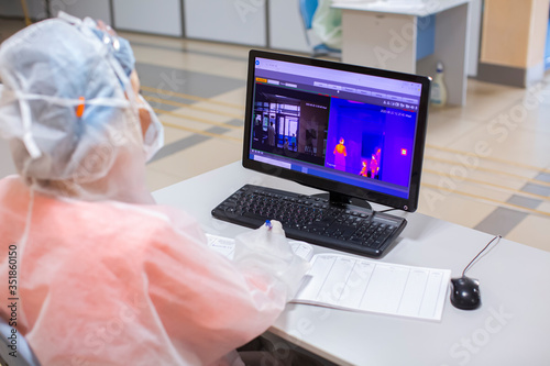Medical worker monitoring people body temperature via infrared camera detector coronavirus COVID-19 pandemy 