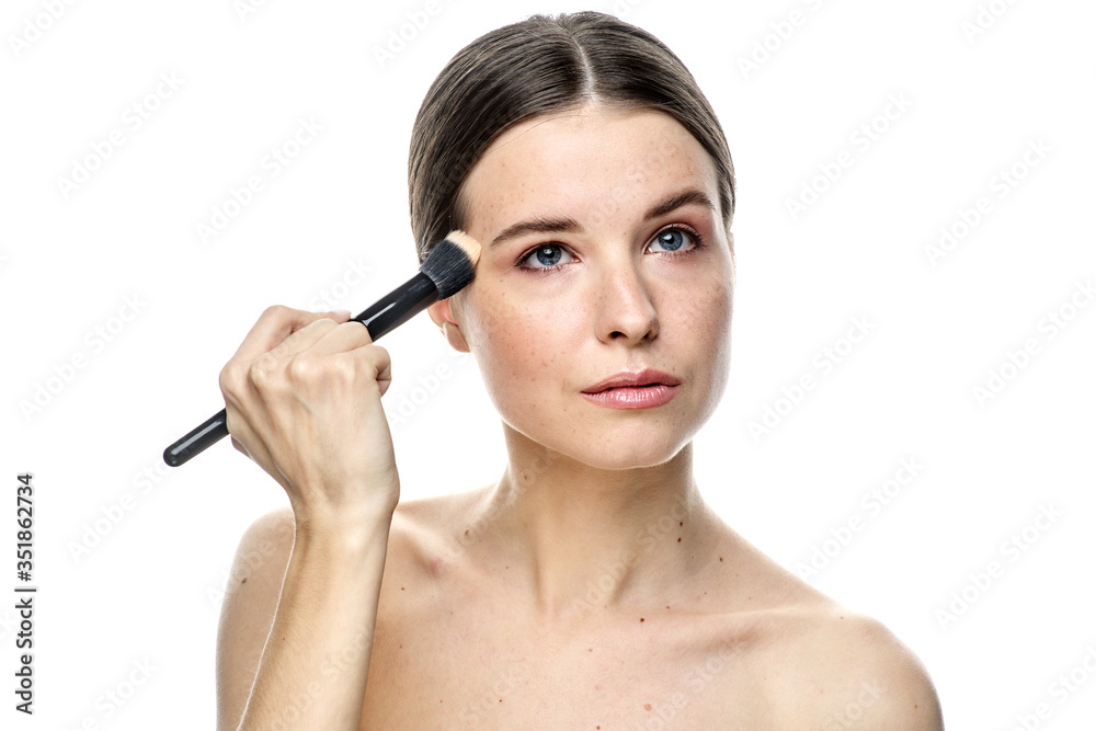 close-up portrait of a girl without makeup with clean skin with a makeup brush in hand, isolated on a white background