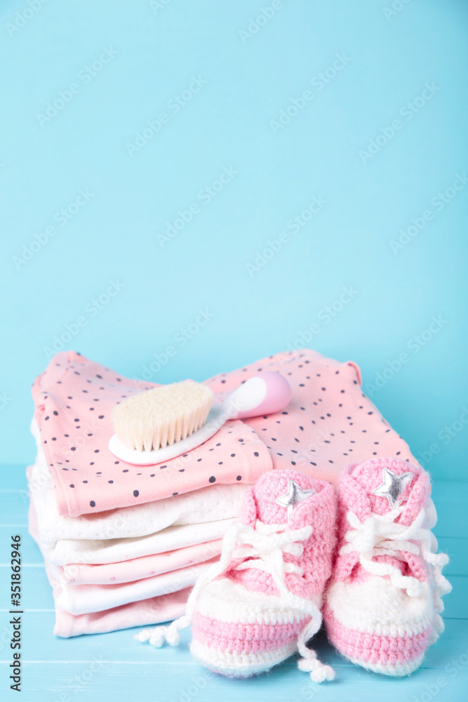 Baby clothes with booties and comb on blue background Baby clothes with booties and comb on blue background