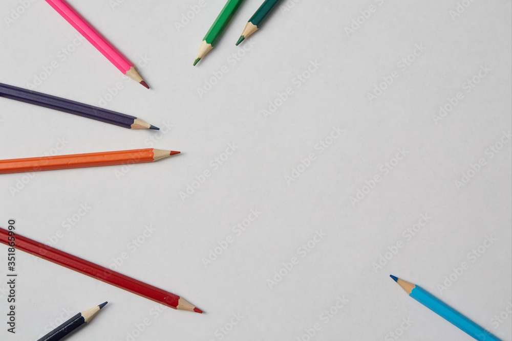 Several colored pencils of various shades lie on a white background, macro photography.