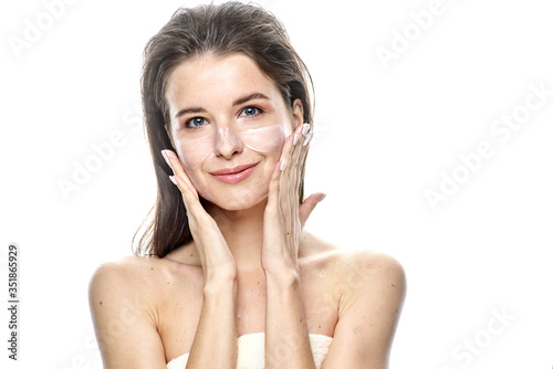 girl with clean skin apply cream on her face. Isolated on a white background