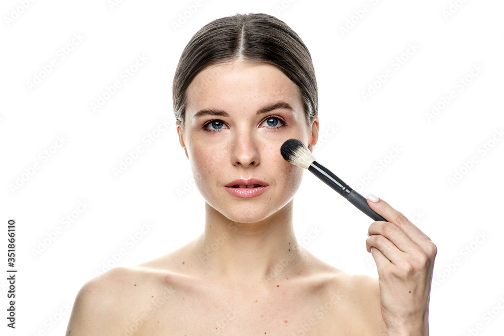 close-up portrait of a girl without makeup with clean skin with a makeup brush in hand, isolated on a white background