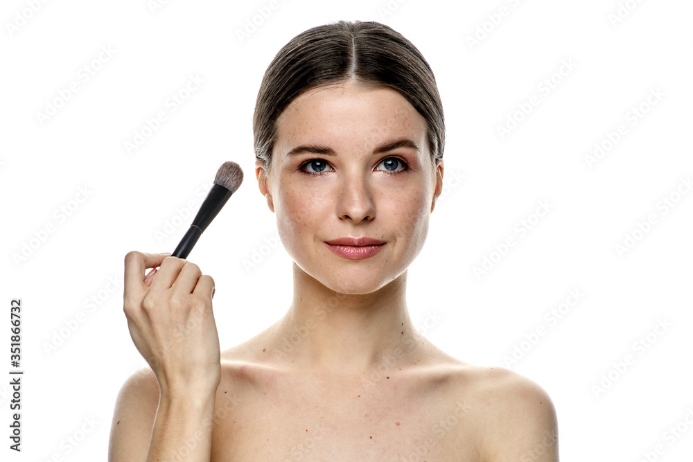 close-up portrait of a young brunette girl with blue eyes with clear skin, doing makeup with makeup brushes, isolated on a white background. High-resolution photos close-up portrait of a young brunette girl with blue eyes with clear skin, doing makeup with makeup brushes, isolated on a white background. High-resolution photos