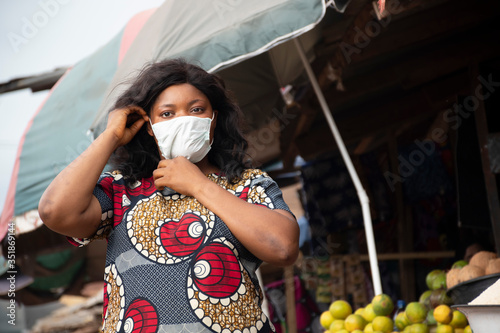 african woman in a local market wearing a face mask