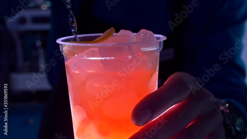 Slow motion pink drink beautifully pour into a glass with ice and lime slices close-up