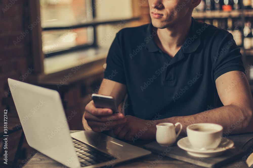 Businessman working on a laptop and using phone in a cafe.