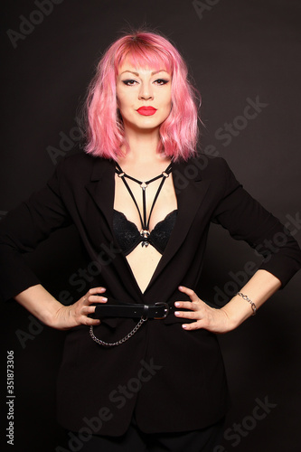 Portrait of a beautiful girl with pink hair in a black jacket on a dark background