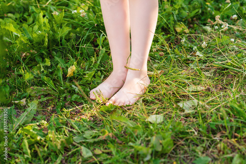 Barefoot of little child standing on a green grass in the park. Child in nature. © okskukuruza