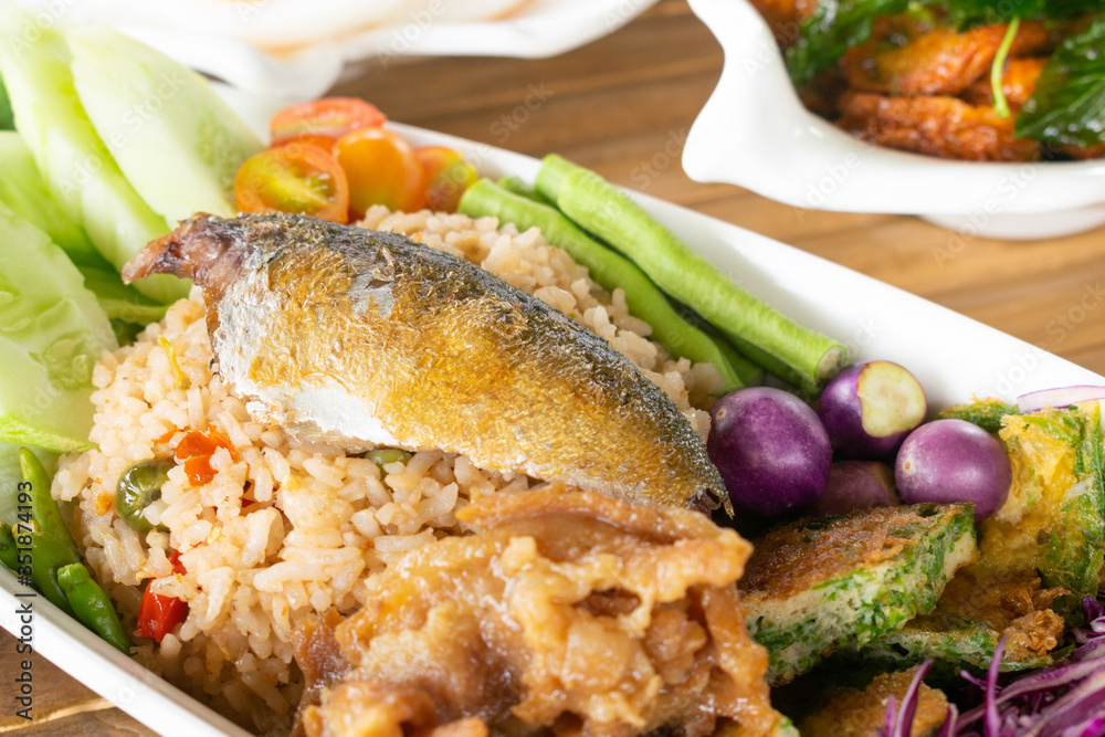Fried rice mixed shrimp paste sauce with mackerel and omelet mixed Cha-om vegetables in white dish. Fried rice mixed shrimp paste sauce with mackerel and omelet mixed Cha-om vegetables in white dish.