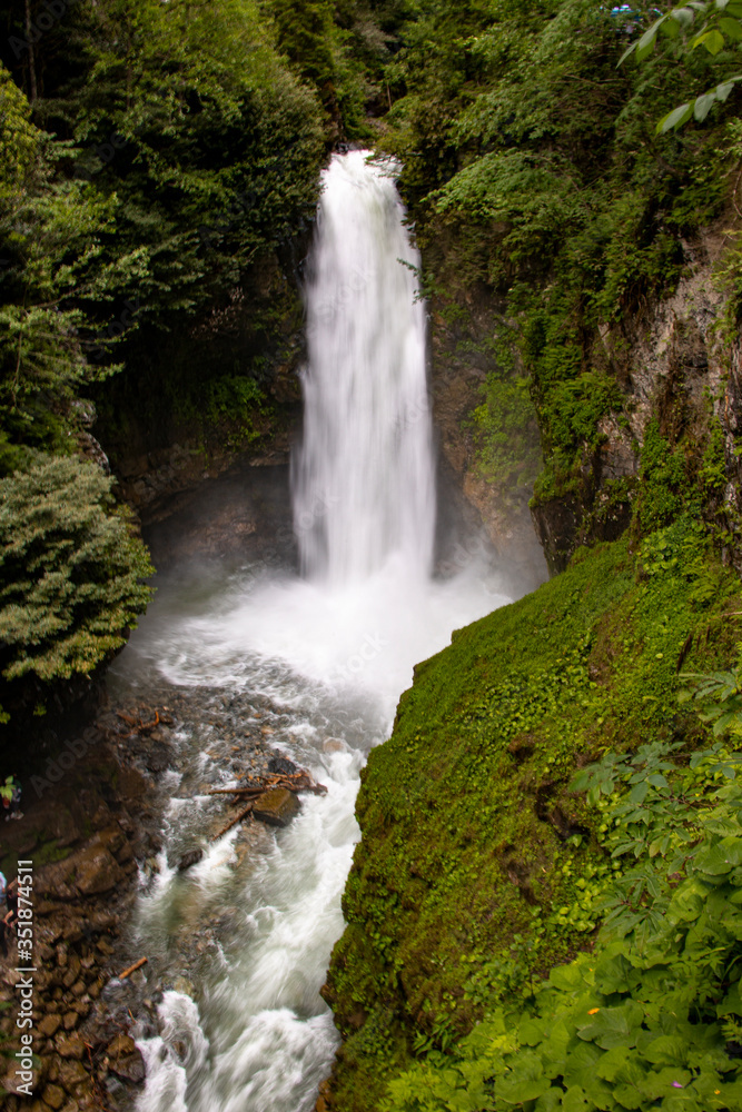 Obraz premium Nature Scene featuring beautiful waterfalls showing water streaming through rock crevices on a sunny day