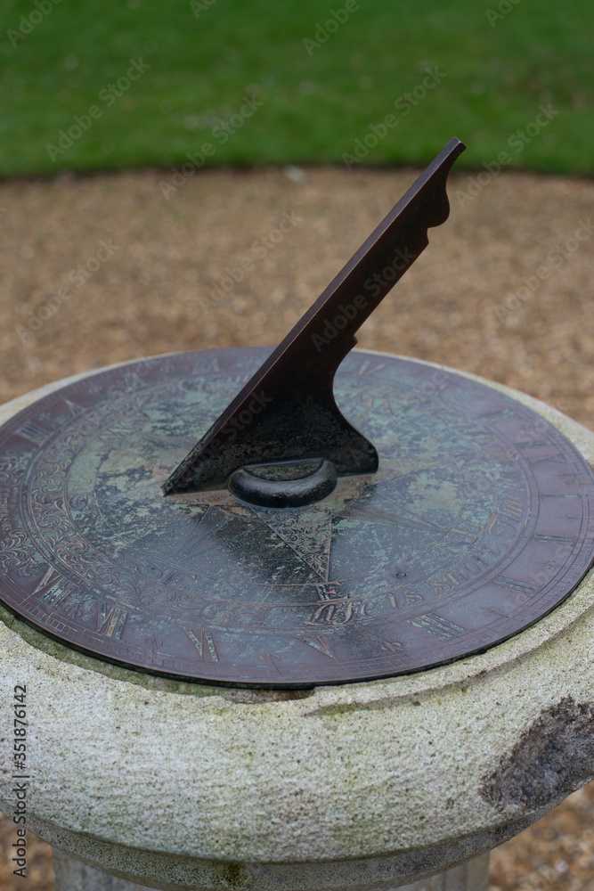 a metal sundial in a garden on a overcast day