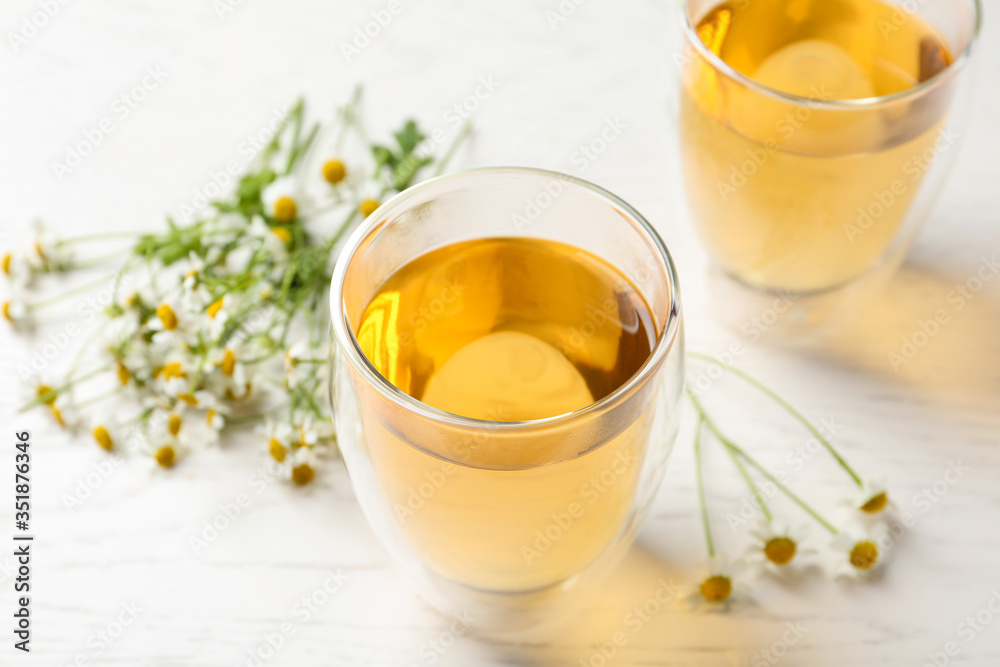 Delicious chamomile tea in glass on white table Delicious chamomile tea in glass on white table