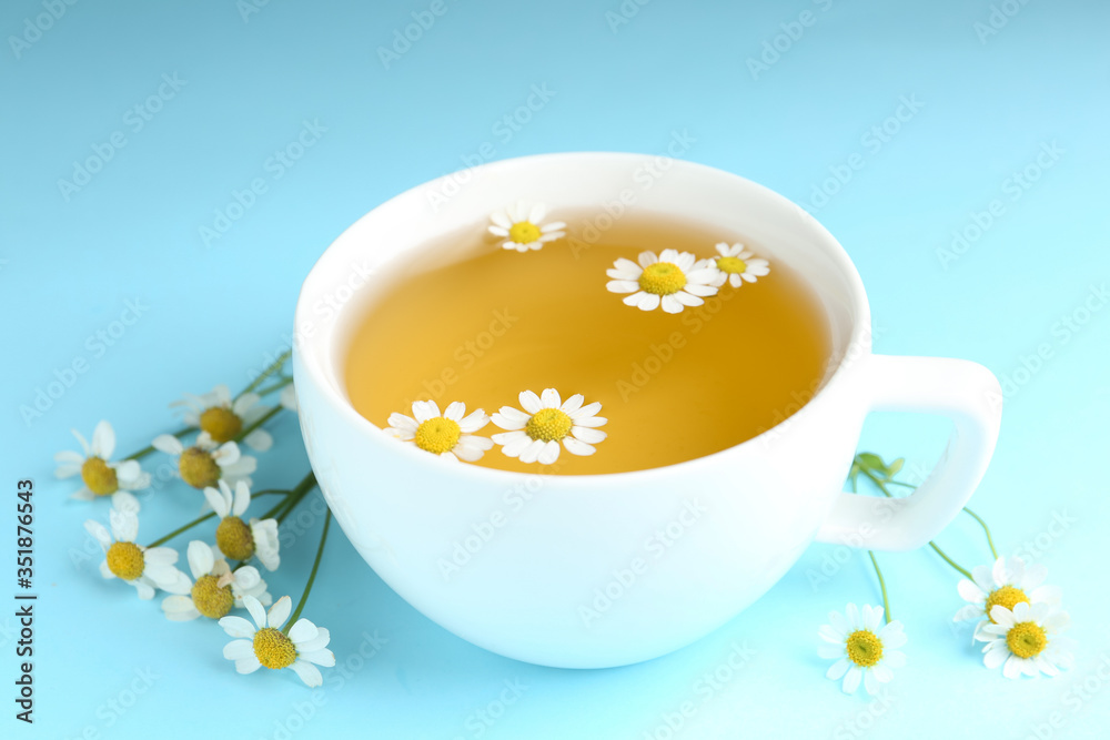 Cup of tea and chamomile flowers on light blue background Cup of tea and chamomile flowers on light blue background