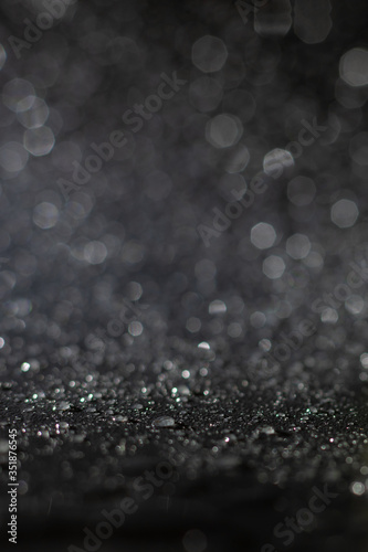 Blurred background for designers made of many bright glowing water drops and sparklings in grey color. Holiday illumination and decoration concept