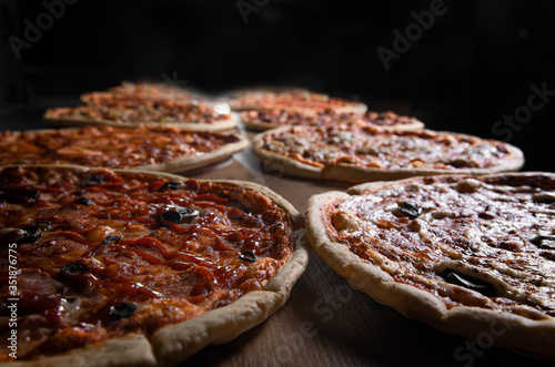  two pizzas on a table on a dark background