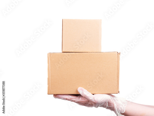 Female hand in a disposable transparent glove holds 2 cardboard boxes - safe delivery of goods, isolate on a white background, copy space © Stanislav Ostranitsa