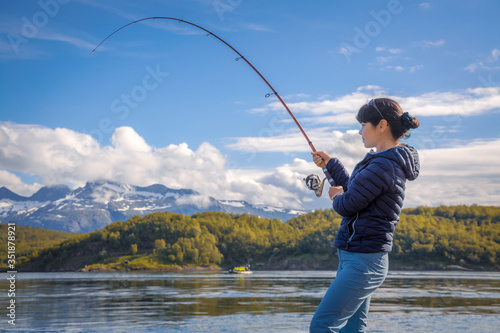 Fotografiet Woman fishing on Fishing rod spinning in Norway.