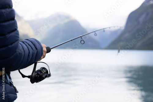 Fototapeta Woman fishing on Fishing rod spinning in Norway.