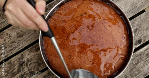 Putting syrup in freshly baked cake