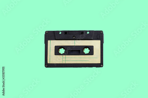 single isolated vintage audio cassette on a green background