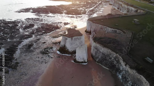 Aerial of White cliffs on beach with white sand and pink sky at sunrise in England 4k cinamatic person walking on beach on goldan sand