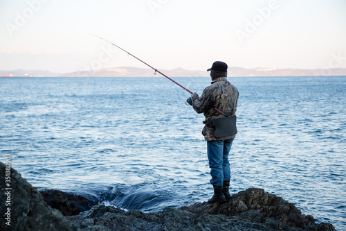 Fisherman catches fish on the rocks
