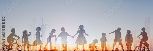 group of children playing with sunset sky and city skyline in background, people silhouette -
