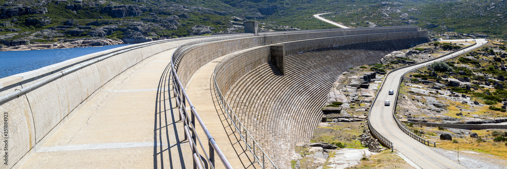 Dam on a mountain river and lake. Huge and long concrete construction