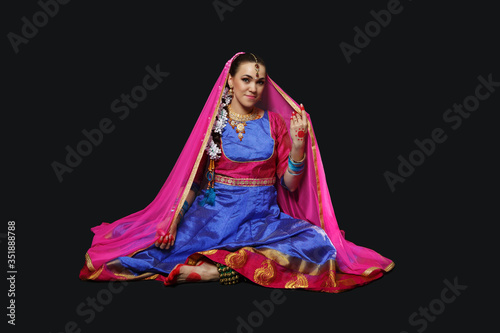 A woman in an Indian suit. A beautiful girl in ornaments is dancing Indian dances. photo