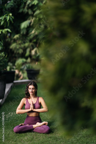 Woman practicing yoga performing yoga-asanas outdoors. Young attractive slim fitness girl in bodysuit relaxing and doing exercises.