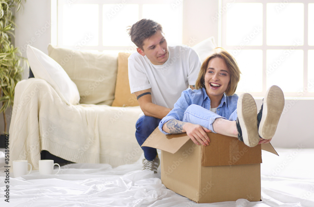 Happy couple having fun and riding in cardboard boxes at new home Happy couple having fun and riding in cardboard boxes at new home