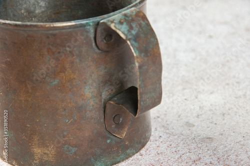 Old brass mug with handle on concrete background