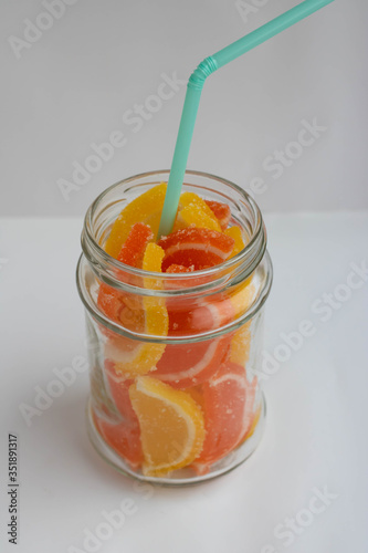 Dessert marmalade in the form of slices of lemon and orange in a jar. Sweet yellow and orange jelly candies. photo