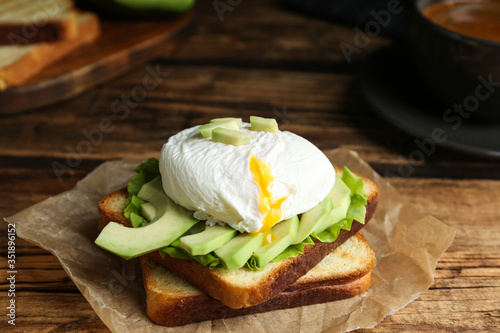Delicious poached egg sandwich served on wooden table