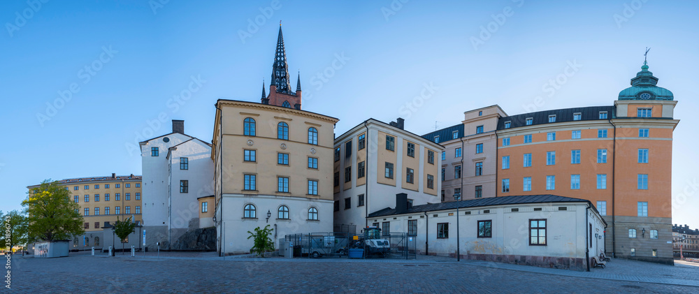 Fototapeta premium Court houses on the island Riddarholmen with the steeple of the church Riddarholmskyrkan at sunrise a spring day in Stockholm.